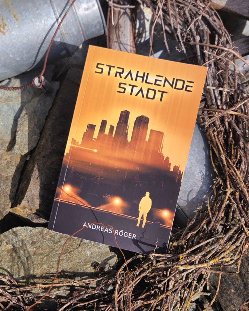 Buch "Strahlende Stadt" liegt auf Steinen, Blechkannen, trockenen Zweigen